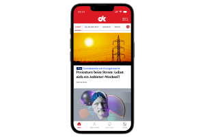 Smartphone mit geöffneter DK-App zeigt Artikel zu Strompreisen und Gesundheitsthemen auf dem Startbildschirm. 