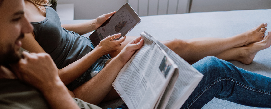 Paar liest gemeinsam die Zeitung analog und digital